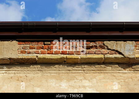 beige brick old evenly plastered wall illuminated by the sun. industrial textured background. with a fragment that has fallen off from old age Stock Photo