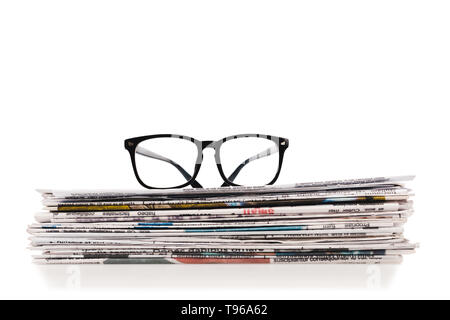 stack of daily newspapers with glasses on top isolated on white Stock Photo