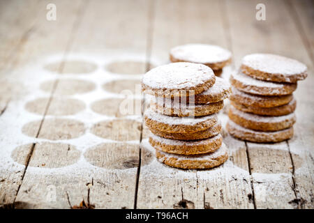 Fresh oat cookies stacks with sugar powder on rustic wooden table background. With copy space. Stock Photo