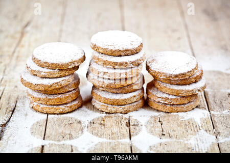 Fresh oat cookies stacks with sugar powder on rustic wooden table background. Stock Photo