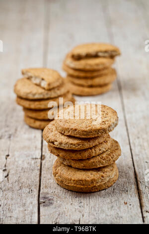 Three stacks of fresh baked oat cookies on rustic wooden table background. Stock Photo