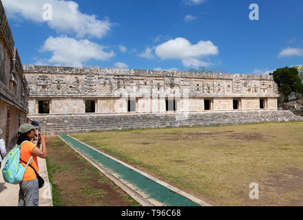 Mexico travel - a tourist taking a photo in the Nunnery Quadrangle, part of the mayan ruins at UNESCO site of Uxmal, Yucatan, Mexico Latin America Stock Photo