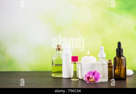 Composition with lot of different size, shape and material beauty cosmetics products bottles arrangement on wooden table with green bokeh studio backg Stock Photo