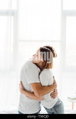 romantic couple in white t-shirts embracing at home Stock Photo