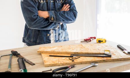 Carpenter working carefully looking at the plans work in carpentry. He is successful entrepreneur at his workplace. hammering a nail Supports On Build Stock Photo