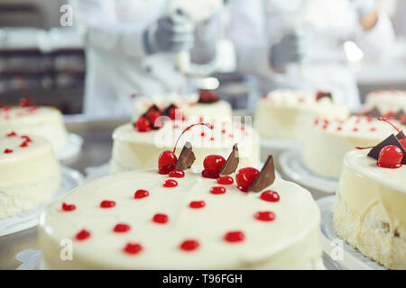 Red cherry on white cake on a table with cakes Stock Photo