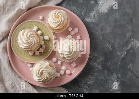 Plate with delicious cupcakes and marshmallows on grey table Stock Photo