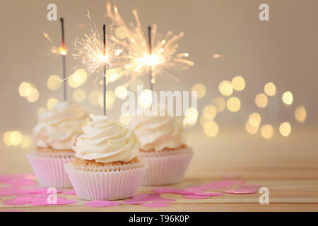 Delicious cupcakes with sparklers on light wooden table Stock Photo