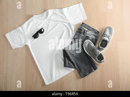 Composition with white t-shirt, jeans and shoes on wooden background Stock Photo