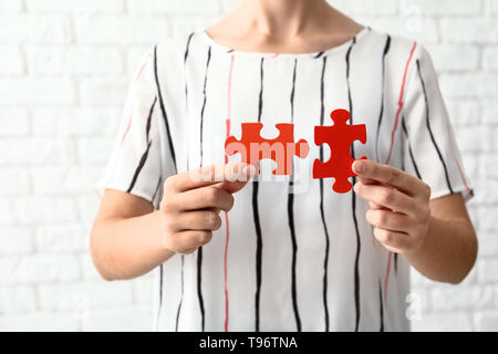 Woman with pieces of color puzzle on brick wall background Stock Photo