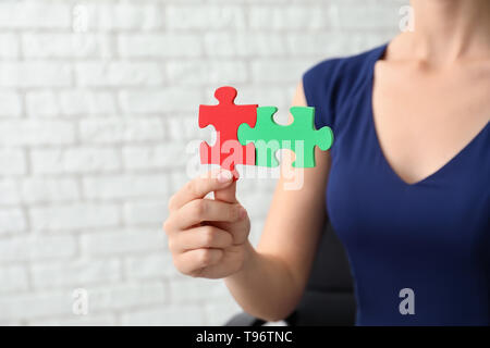 Woman with pieces of color puzzle on brick wall background Stock Photo