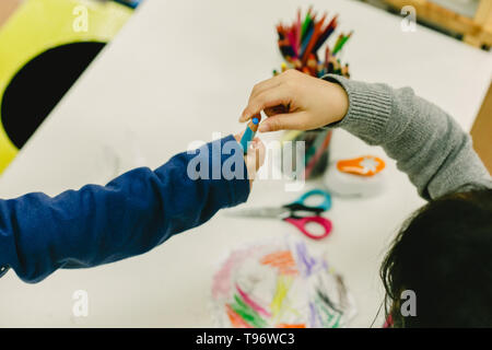 Two students share pencils in a nursery school, concept of collaboration Stock Photo