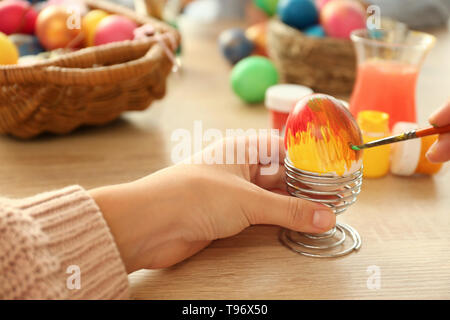 Woman painting Easter eggs on table Stock Photo