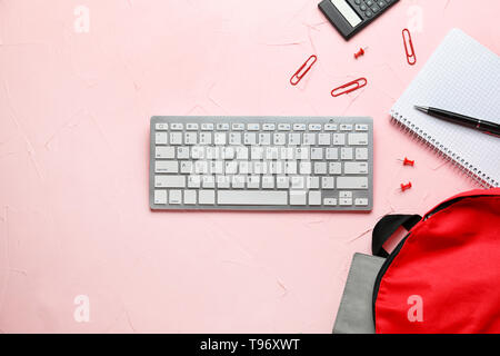 Composition with rucksack, keyboard and school stationery on color background Stock Photo