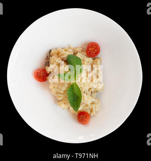 Creamy risotto in porcelain plate isolated on black background Stock Photo