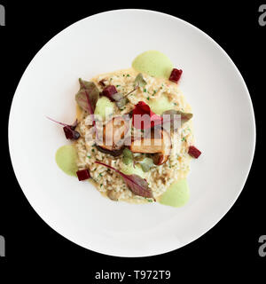 Risotto with fried porcini mushrooms on white plate, isolated on black background with clipping path Stock Photo