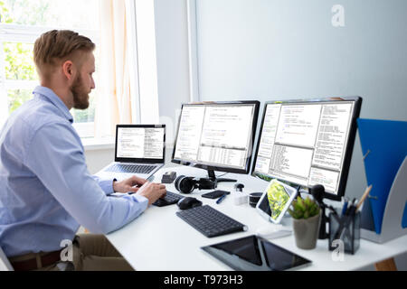 Computer programmer writing program code on computer in office Stock Photo