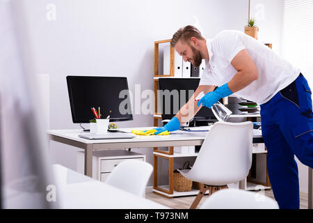 Janitor cleaning white desk in modern office Stock Photo