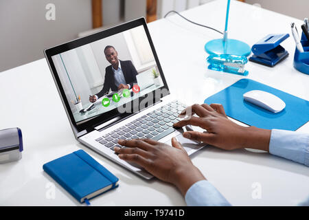 Close-up Of A Businessperson's Videoconferencing With Male Colleague On Laptop Stock Photo