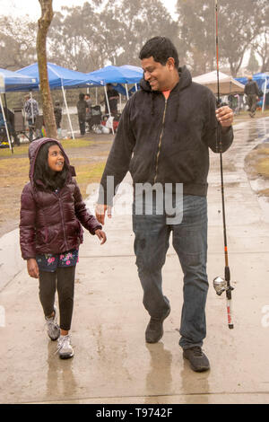 A Pakistani American father and his daughter go fishing on a rainy day at a pond in Fountain Valley, CA. Stock Photo