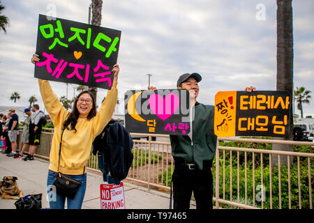 A yong Asian American couple hold a sign reading 'Amazing Mom' in Korean as they encourage her mother in a 10K race in Huntington Beach, CA. Stock Photo