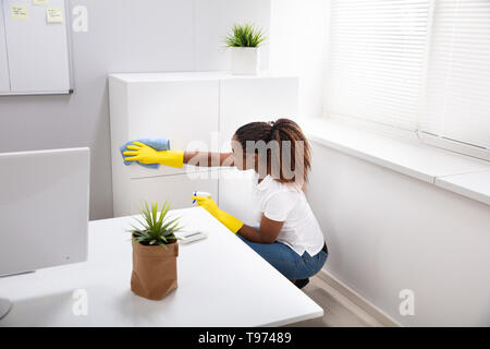 Smiling Young Woman Cleaning Furniture With Spray Bottle At Home Stock Photo