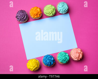 Different cupcakes with sheet of paper on color background Stock Photo