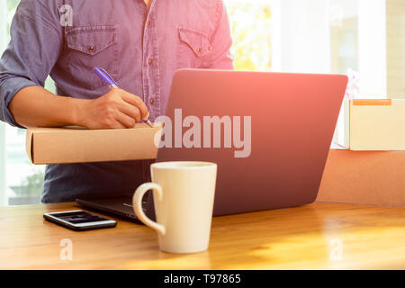 SME Business man writing address on parcel with labtop on the table. Stock Photo