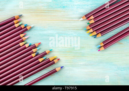 Many different colored pencils forming a frame, shot from the top on a teal blue background with copy space Stock Photo
