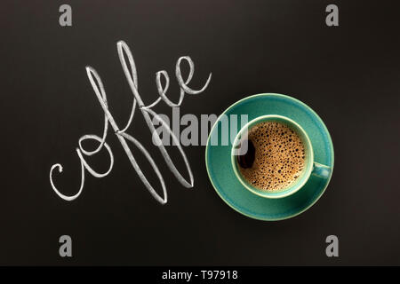 A cup of coffee on a black background. shot from the top with chalk lettering and a place for text Stock Photo