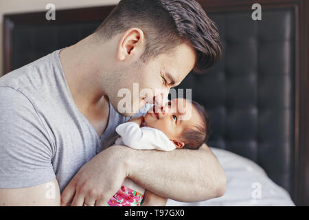 Closeup of young Caucasian father with newborn mixed race Asian Chinese baby. Male man parent holding child daughter son. Authentic lifestyle touching Stock Photo