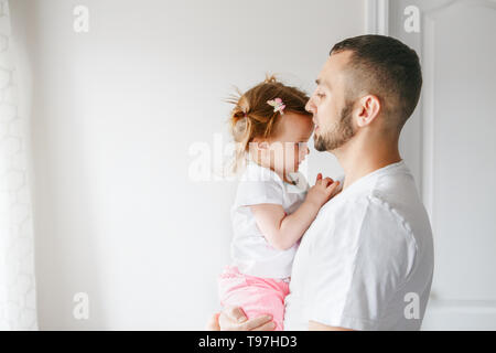 Caucasian father talking speaking with toddler baby girl. Male man parent holding embracing child. Authentic lifestyle touching tender moment. Single  Stock Photo