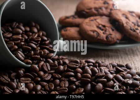 coffee beans crumbled with a cup which is worth on light burlap, in the background plate of cookies Stock Photo