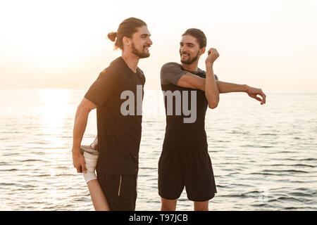 Two twin brothers doing exercises at the beach together Stock Photo