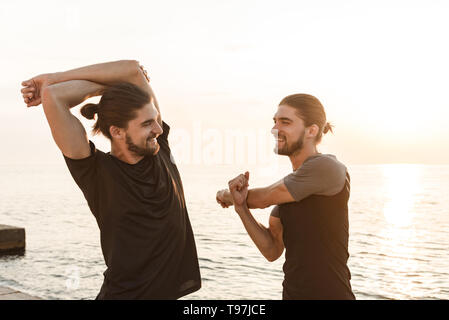 Two twin brothers doing exercises at the beach together Stock Photo