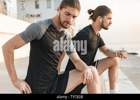 Two twin brothers doing exercises at the beach together Stock Photo