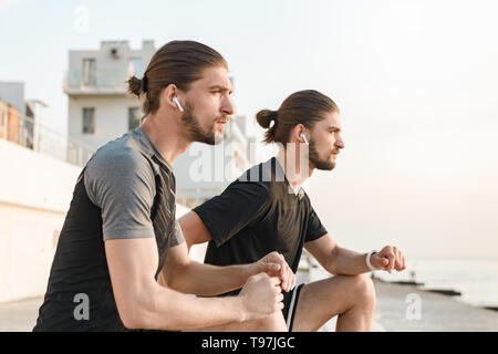 Two twin brothers doing exercises at the beach together Stock Photo