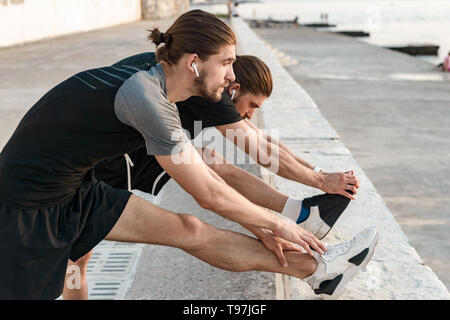 Two twin brothers doing exercises at the beach together Stock Photo