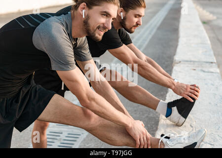 Two twin brothers doing exercises at the beach together Stock Photo