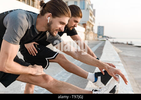 Two twin brothers doing exercises at the beach together Stock Photo
