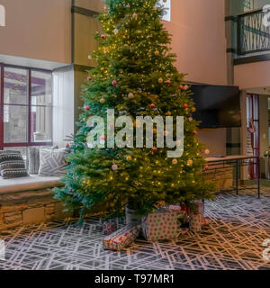 Square Traditional Christmas tree decorated with baubles lights and gift boxes Stock Photo