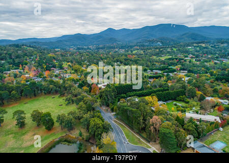 Scenic gree rural area with houses among trees surrounded by mountains in Victoria, Australia - aerial landscape Stock Photo