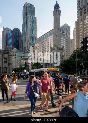 Afternoon sun shines on passersby beside the Chicago Water Tower at 806 North Michigan Avenue along the Magnificent Mile shopping district in the Near North Side community area of Chicago, IL. The tower was constructed to house a large water pump, intended to draw water from Lake Michigan. Built in 1869, it is the second-oldest water tower in the United States. Stock Photo