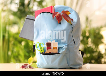 Backpack with school supplies on natural background Stock Photo