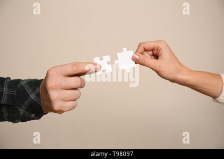 Male and female hands with pieces of puzzle on light background Stock Photo