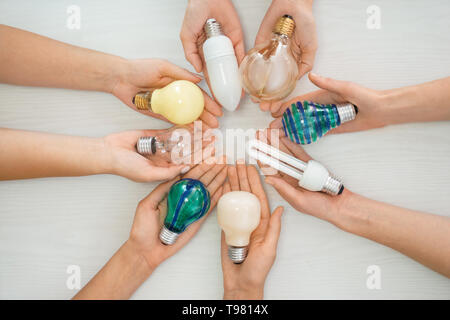 Female hands with different light bulbs on light background Stock Photo