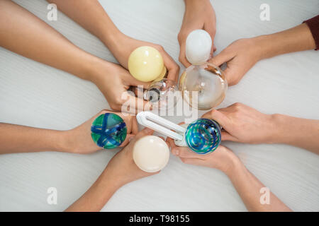 Female hands with different light bulbs on light background Stock Photo