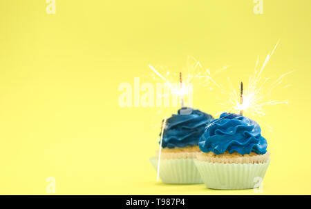 Tasty cupcakes with sparklers on color background Stock Photo