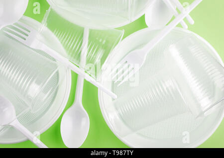 White Disposable cups, plates, forks, knives isolated on light green background close-up - Environmental problem concept Stock Photo