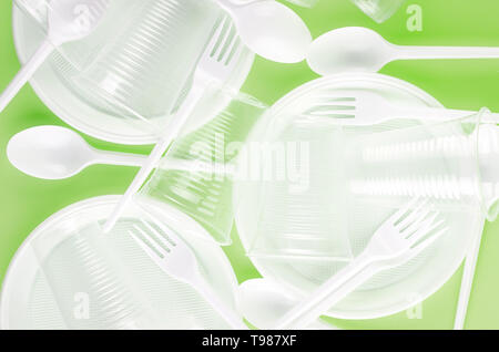White Disposable cups, plates, forks, knives isolated on light green background close-up - Environmental problem concept Stock Photo